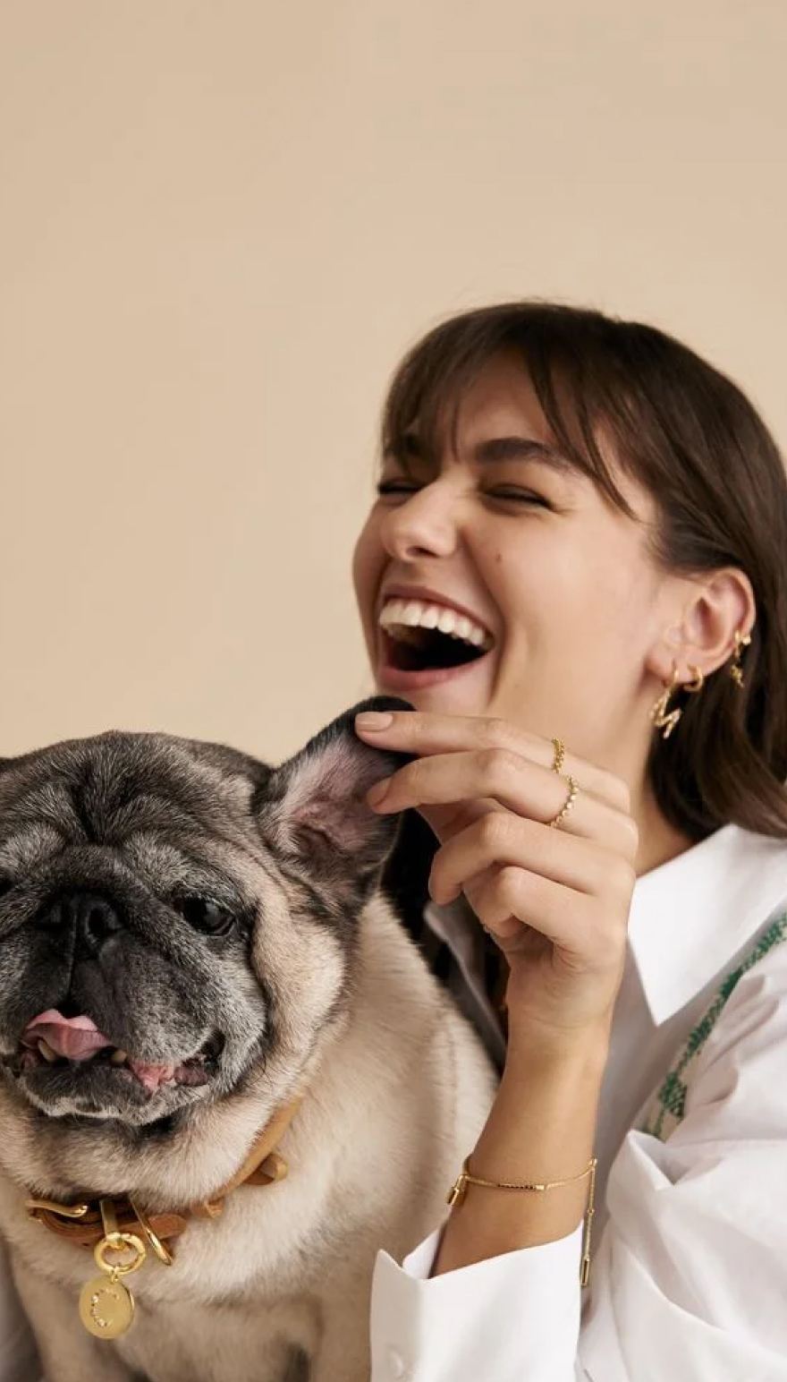 A woman laughing with her pug