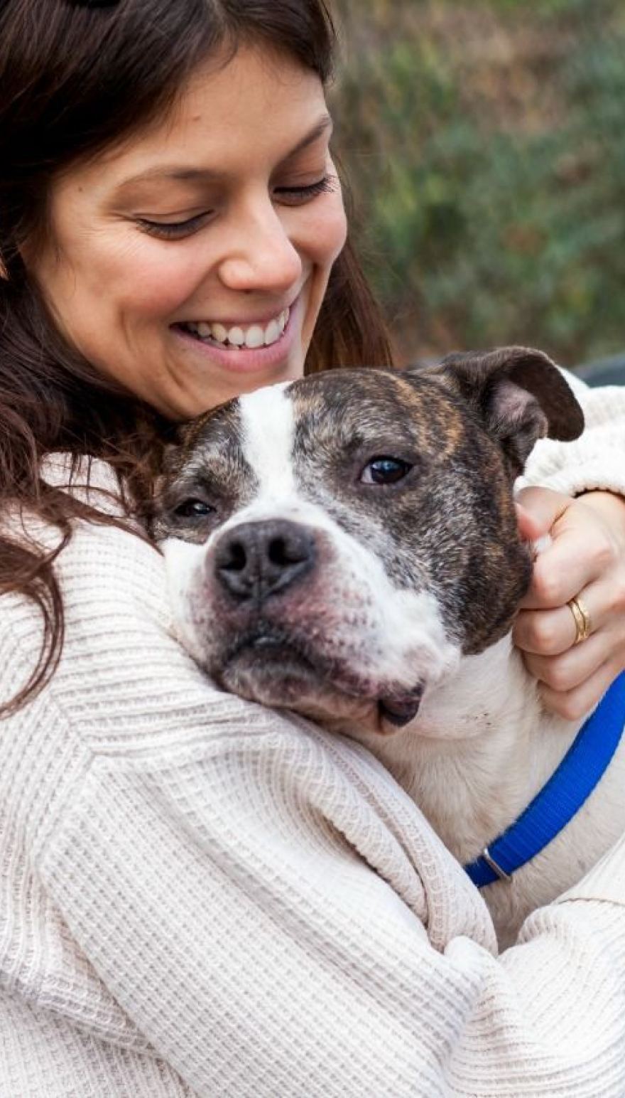A smiling woman hugging her Staffy